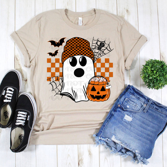Ghost With Beanie DTF Heat Transfer, Halloween-themed ghost illustration wearing a checkered beanie, surrounded by bats, spider web, and a pumpkin with candy inside on a beige T-shirt.