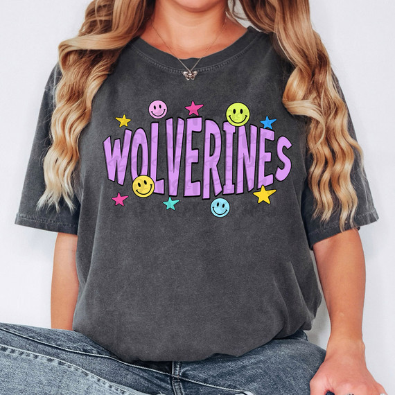 Wolverines Happy Face DTF Heat Transfer, colorful graphic t-shirt design with the word 'Wolverines' in large purple letters and cheerful smiley faces and stars.