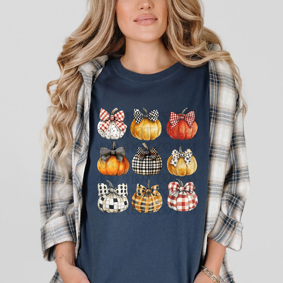 Patterned Pumpkins DTF Heat Transfer, woman wearing a navy T-shirt with colorful pumpkin patterns featuring different plaid and polka dot bow designs.
