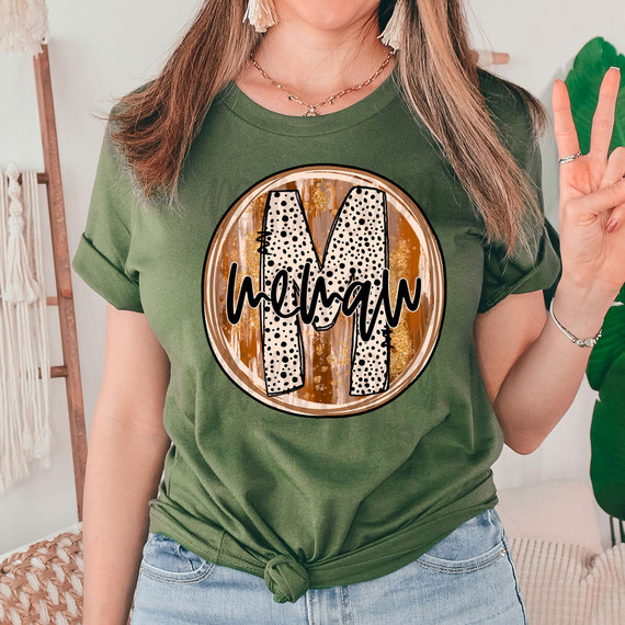 Memaw Fall Brushstrokes DTF Heat Transfer, product design featuring a large letter 'M' with brushstroke fall colors and the word 'mamaw' written across in black, on a woman's green t-shirt.