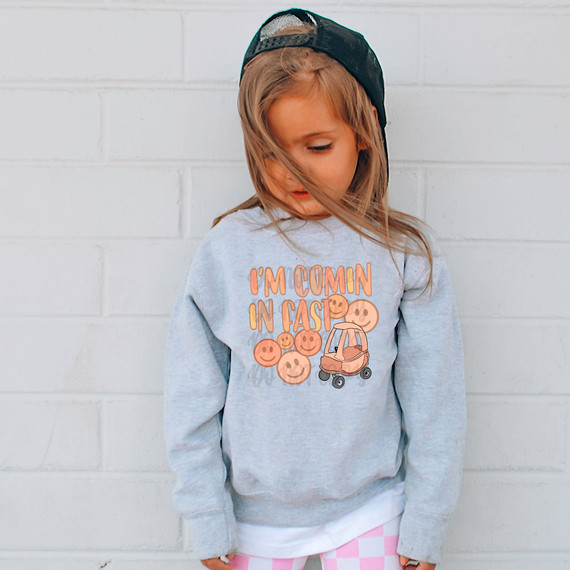 I'm Comin In Fast DTF Heat Transfer, a child's graphic sweatshirt featuring a design with smiling faces and a small car.
