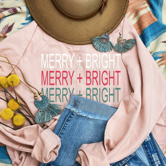 Merry + Bright DTF Heat Transfer, colorful text design on a pink sweatshirt with accessories and hat.
