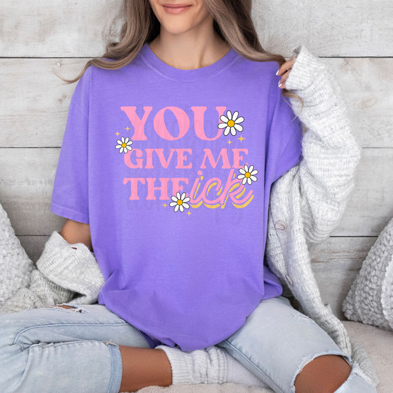 You Give Me The Ick DTF Heat Transfer, a colorful design with playful text and flower graphics on a purple t-shirt worn by a woman.