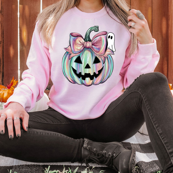 Iridescent Peeking Ghost Jack O'Lantern DTF Heat Transfer, shiny holographic pumpkin with a bow and ghost decoration on a pink sweatshirt.
