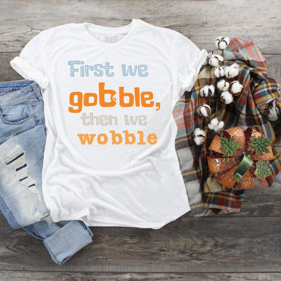 First we gobble then we wobble Sublimation Transfer T-shirt, white T-shirt with text design, paired with ripped jeans and fall-themed accessories.