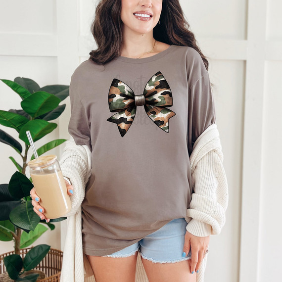 Camo Bow DTF Heat Transfer, product image showing a woman wearing a gray T-shirt with a camouflage bow design heat transfer on the front.