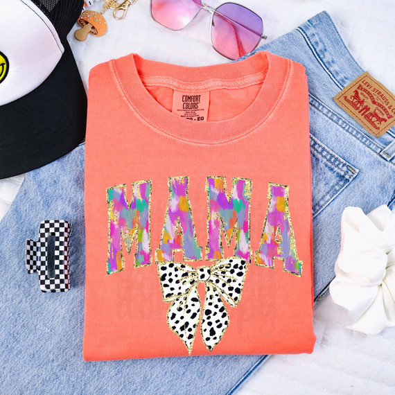 Mama Dot Bow Faux Glitter DTF Heat Transfer, colorful and glittery butterfly design with the word 'MAMA' on an orange t-shirt.