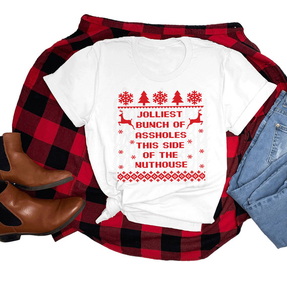Jolliest Bunch Of Assholes This Side of the Nuthouse DTF Heat Transfer, white t-shirt with red holiday themed text and graphics, surrounded by plaid shirt, jeans, and boots.
