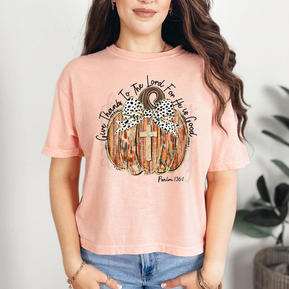 Give Thanks To The Lord For He Is Good Coquette Pumpkin DTF Heat Transfer, a woman wearing a pink T-shirt with a colorful pumpkin design and the biblical quote from Psalm 136:1.