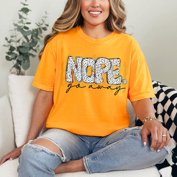 Nope. Go Away DTF Heat Transfer, a woman wearing an orange T-shirt with the phrase 'NOPE. go away' printed on it, sitting on a sofa.