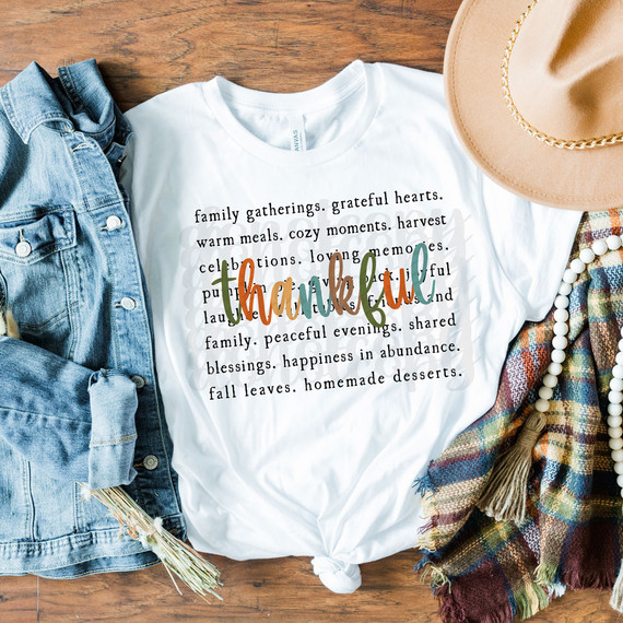 Thankful Fall Colors DTF Heat Transfer, a colorful fall-themed design with the word 'thankful' in mixed colors on a white t-shirt, accompanied by autumn accessories like denim jacket, hat, pearl necklace, and plaid scarf.