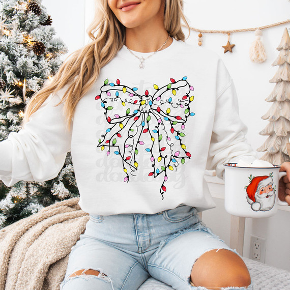 Bright Christmas Light Bow DTF Heat Transfer, colorful Christmas light string shaped like a bow on a woman's white sweatshirt.