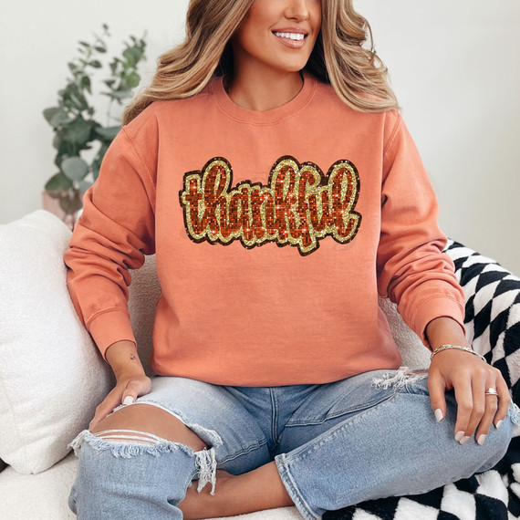 Thankful Faux Sequins DTF Heat Transfer, a woman wearing a peach sweatshirt with a sequin thank you design.
