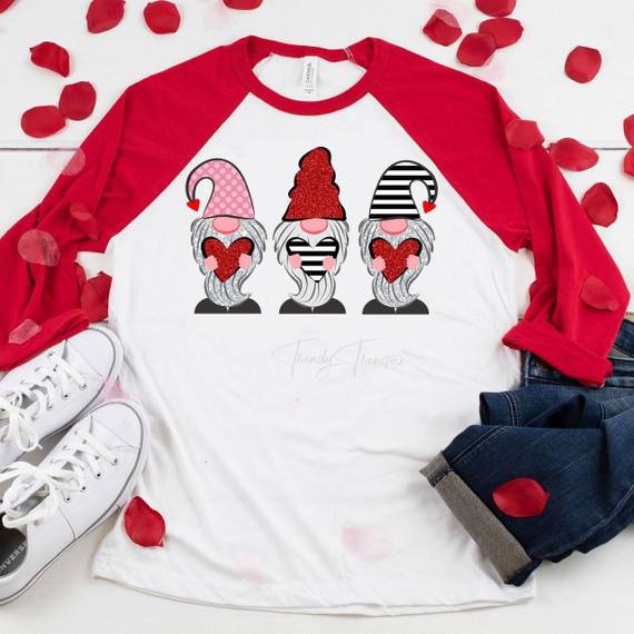 Glitter Gnome Valentine Sublimation Transfer, a graphic design featuring three gnomes with glitter beards holding hearts, on a white and red raglan t-shirt.