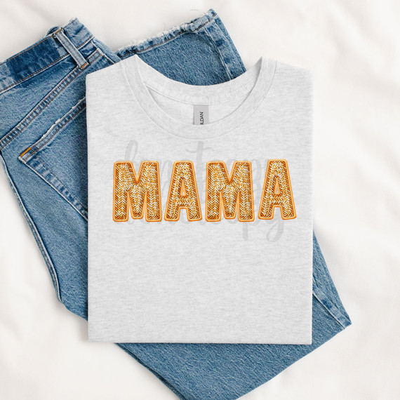 Orange Groovy Faux Sequins Letters DTF Heat Transfer, close-up image of a T-shirt featuring decorative faux sequin letters spelling 'MAMA' in orange color, laid on a pair of blue jeans.