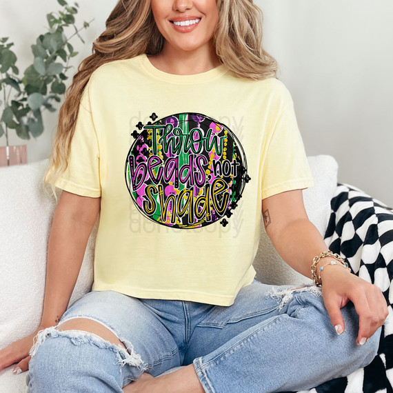 Throw Beads Not Shade DTF Heat Transfer, woman wearing a yellow t-shirt with colorful throw beads design and the phrase 'Throw beads not shade' for DIY apparel customization.