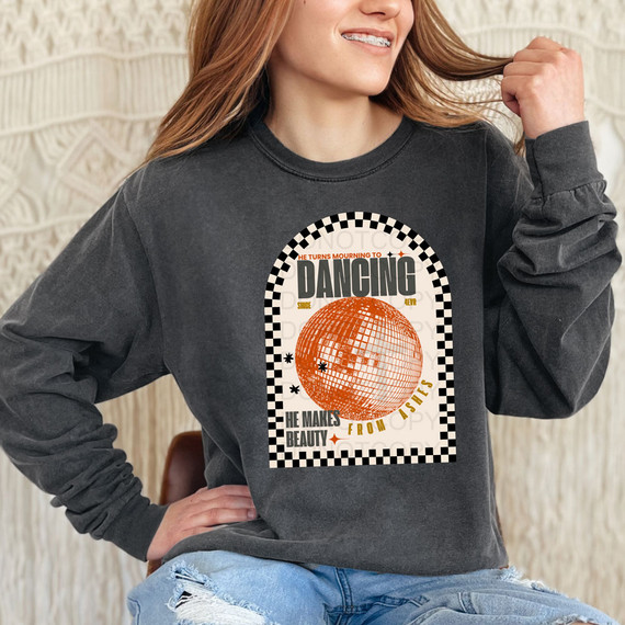 He Turns Mourning To Dancing DTF Heat Transfer, a woman wearing a black sweatshirt with a vibrant orange disco ball graphic and motivational text in a stylish design.
