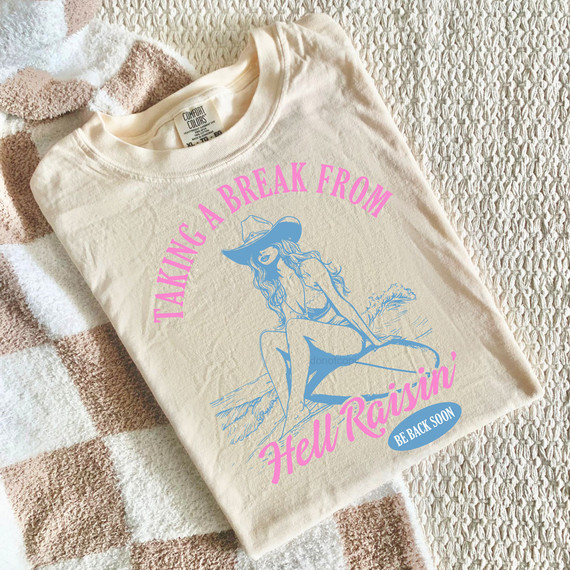 Taking A Break From Hell Raisin' DTF Heat Transfer, graphic illustration of a woman in a hat sitting on a floatation device in the water with pink and blue text.