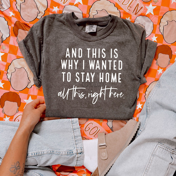 Product: White DTF Heat Transfer, Image description: Gray T-shirt with white text that reads 'And this is why I wanted to stay home all this, right here', laid on a colorful background with illustrated faces and stars.