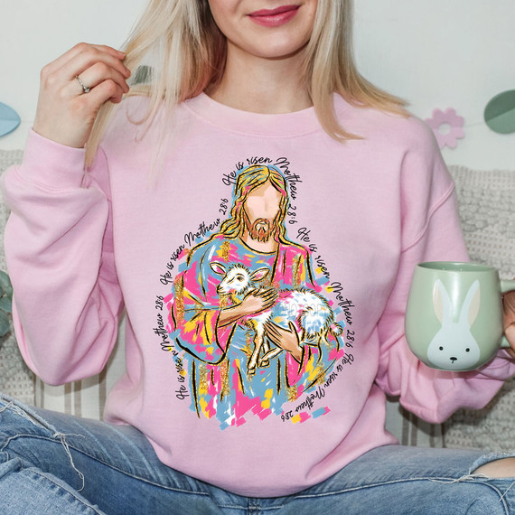 Painted He Is Risen Matthew 28:6 DTF Heat Transfer T-shirt design, Christian Jesus Christ holding a lamb with scripture quote, pink sweatshirt with colorful illustration, religious apparel for Easter or faith-based occasions