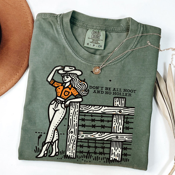 Don't Be All Hoot And No Holler DTF Heat Transfer T-Shirt, green color with graphic design of a woman in cowboy outfit leaning on a wooden fence