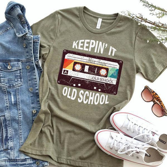 Keepin' It Old School Screen Print Heat Transfer, a vintage cassette tape graphic on a khaki T-shirt with white text, accompanied by denim jacket, sunglasses, and white sneakers with red accents.