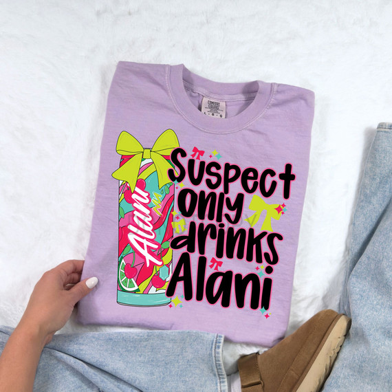Suspect Only Drinks Alani, a colorful heat transfer design on a lavender t-shirt featuring a stylized Alani drink can with a yellow bow, vibrant graphics, and playful text.