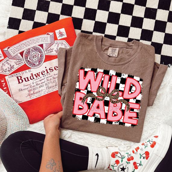 Wild Babe Leopard Bow DTF Heat Transfer, a graphic design featuring bold pink text and a leopard pattern bow, placed on a brown t-shirt.