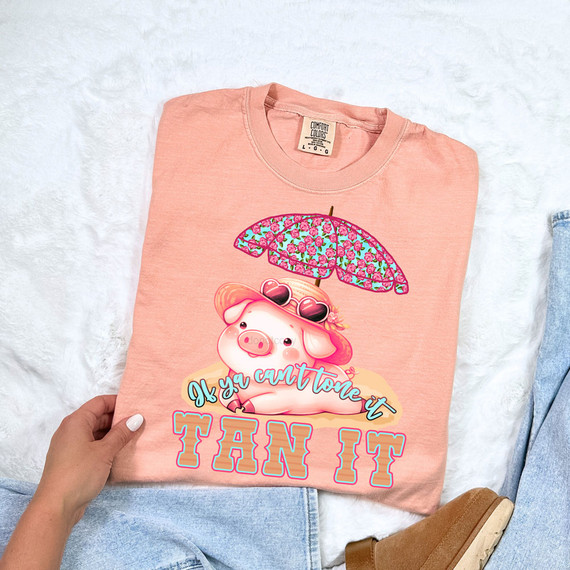 If Ya Can't Tone It Tan It DTF Heat Transfer, pink t-shirt with a cute pig under an umbrella and the slogan 'If ya can't tone it TAN IT' in bright colors.