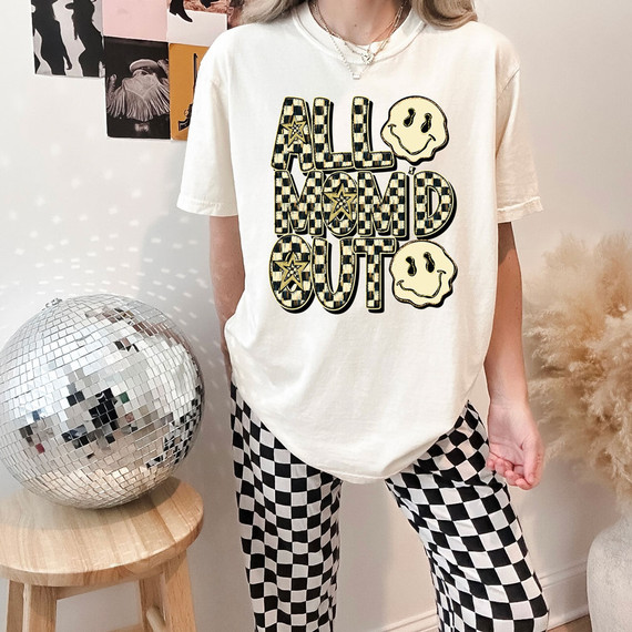 All Mom'd Out Retro DTF Heat Transfer, graphic t-shirt featuring bold checked and star-patterned text with smiley face graphics.