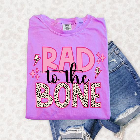 Rad To The Bone DTF Heat Transfer, pink T-shirt with 'Rad to the Bone' graphic in bold, leopard print and pink text, decorated with lightning bolts and star accents.