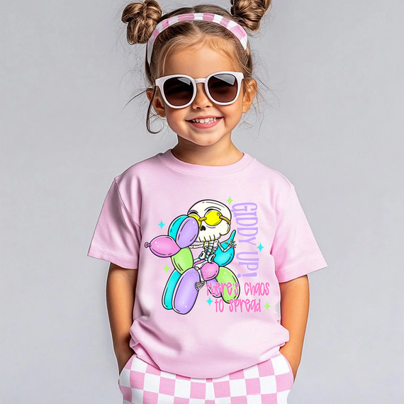 Giddy Up There's Chaos To Spread DTF Heat Transfer, a colorful graphic t-shirt featuring a skeleton with balloons and the playful phrase 'There's chaos to spread' on a young girl wearing sunglasses and a pink checkered outfit.