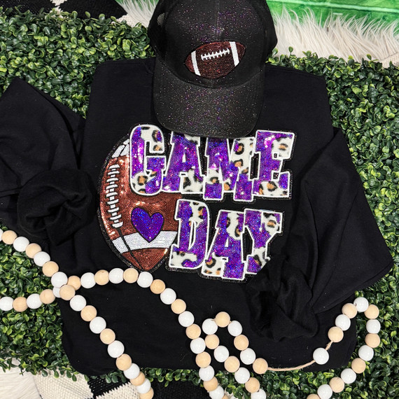 Purple Football Leopard & Sequins Patch, black t-shirt with leopard and purple glitter patches, paired with a black glittery cap with football design, and a string of white and beige beads, placed on a green decorative background.