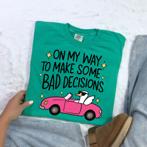 On My Way to Make Bad Decisions DTF Heat Transfer, a colorful printed t-shirt with a pink car and a flying duck illustration and playful black text.