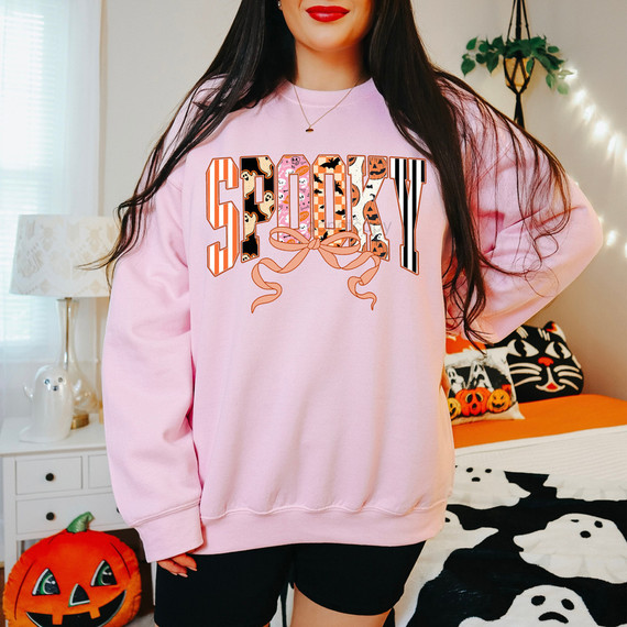 Spooky Patterned Bow DTF Heat Transfer, Halloween-themed design with colorful spooky patterns and a bow on a pink sweatshirt.