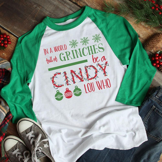 In a World Full Screen Print Heat Transfer, holiday-themed Christmas T-shirt with green and red text and ornaments on a white and green baseball tee