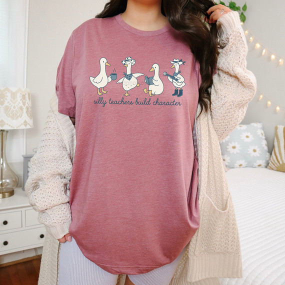 Silly Teachers Build Character DTF Heat Transfer, a pink shirt featuring cartoon teacher animals with the text 'silly teachers build character' for educational and humorous purposes.