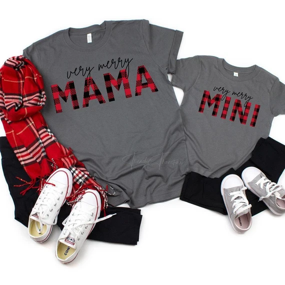 Very Merry Mama Buffalo Plaid Adult Screen Print Transfer, gray T-shirts with 'Very Merry MAMA' in buffalo plaid letters and matching mini T-shirt, paired with sneakers and a red buffalo plaid scarf.