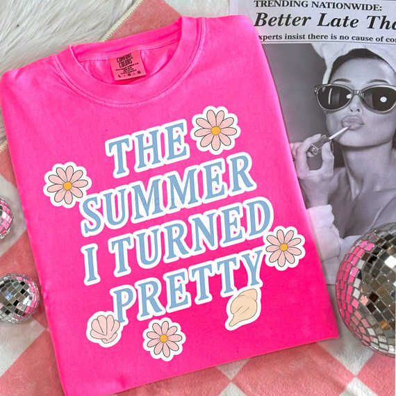 The Summer I Turned Pretty DTF Heat Transfer, a pink T-shirt with a colorful graphic design and floral accents.