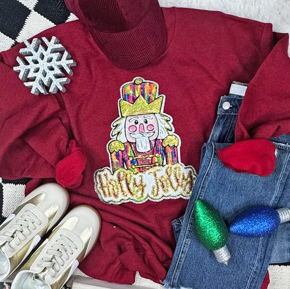 Nutcracker Chenille and Sequin Patch, colorful embroidered patch featuring a nutcracker with a crown and the words 'Magic Joy' on a red sweatshirt.