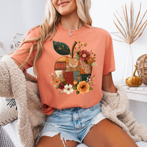 Patchwork Apple DTF Heat Transfer, colorful apple-shaped patchwork design with flowers and leaves on a woman's coral t-shirt.