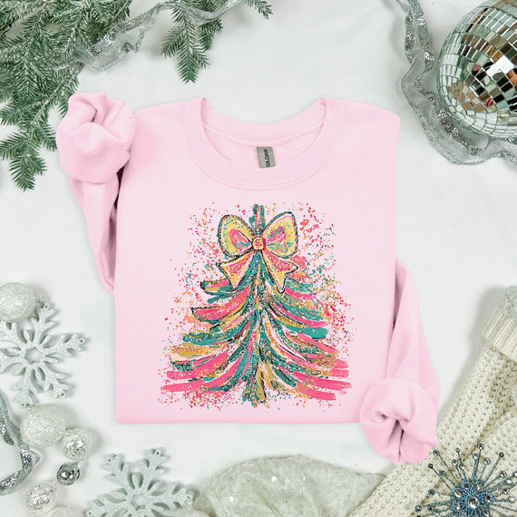 Sparkly Christmas Tree DTF Heat Transfer, pink sweatshirt with a colorful glittery Christmas tree design with a pink bow on top, holiday decorations around it.