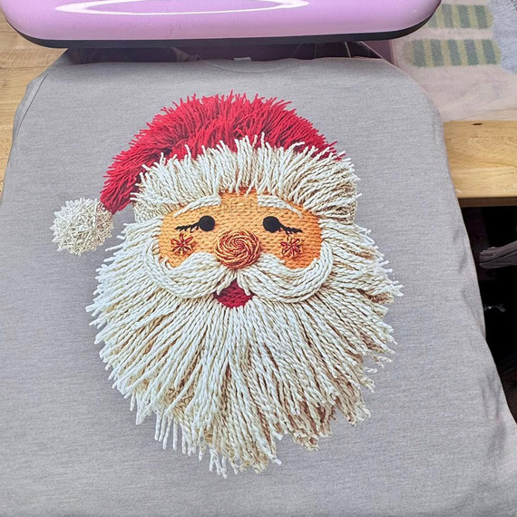 Faux Yarn String Santa DTF Heat Transfer, festive Santa Claus face with a fluffy beard, red hat with white pom-pom, embroidered eyes, nose, and cheerful expression.