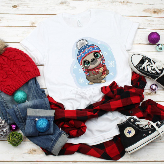 Winter Sloth with Coffee Sublimation Transfer, cute sloth wearing a winter hat and holding a coffee cup, on a white t-shirt surrounded by casual winter clothing and holiday decorations.