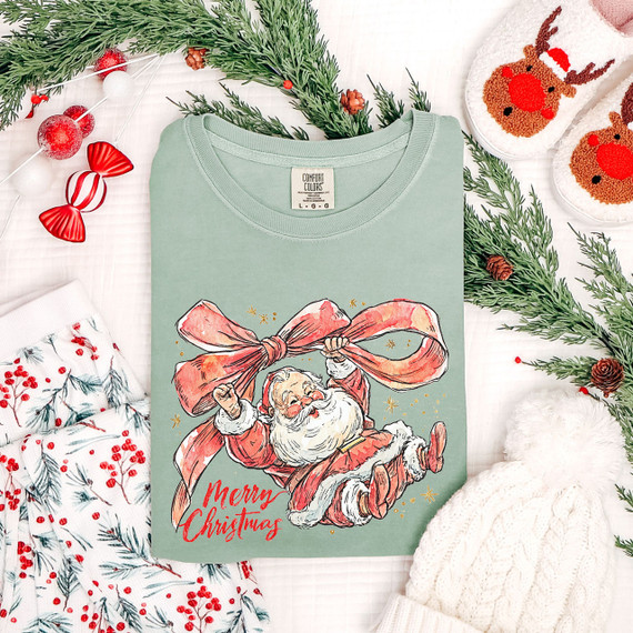 Santa with Bow Merry Christmas DTF Heat Transfer, festive Christmas-themed product featuring a cheerful Santa holding a large bow, surrounded by holiday decorations and cozy accessories.