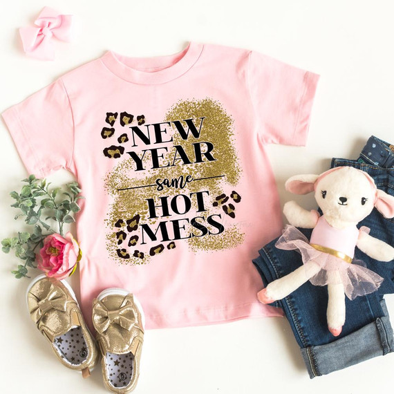 New Year Same Hot Mess YOUTH Screen Print Transfer, pink children's t-shirt with glitter and leopard print design, surrounded by gold shoes, a plush toy, jeans, and a pink bow.