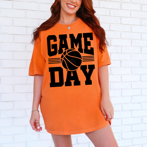 Game Day Basketball BLACK DTF Heat Transfer, product image showing a woman wearing an orange T-shirt with a black basketball and text design.