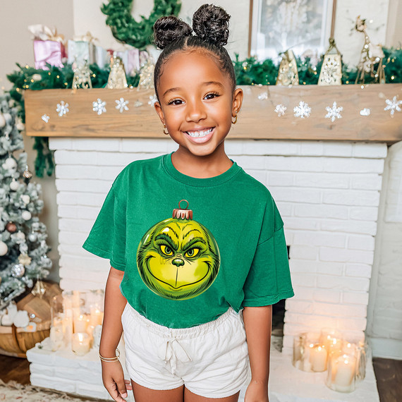 Green Guy Ornament DTF Heat Transfer, festive Christmas ornament design on a smiling girl's green t-shirt.