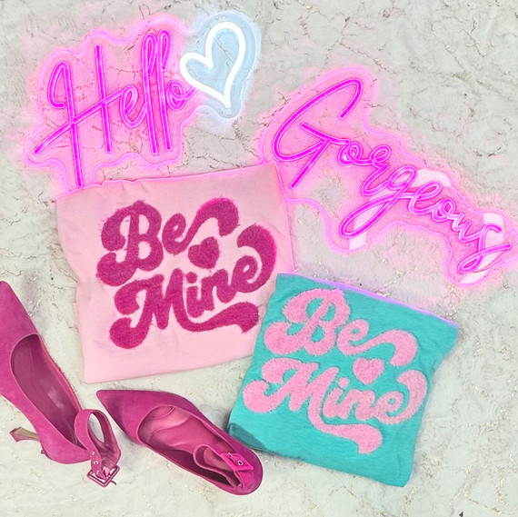 Be Mine Fluffy Patch, pink and turquoise fluffy patches with love-themed designs, including hearts and the words 'Be Mine', pink heels shoes with ankle straps, and neon signs saying 'Hello' and 'Gorgeous' in bright pink and blue colors.