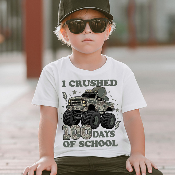 I Crushed 100 Days of School Camo Monster Truck DTF Heat Transfer, a young boy wearing sunglasses, a baseball cap, and a white T-shirt with a camo monster truck graphic.